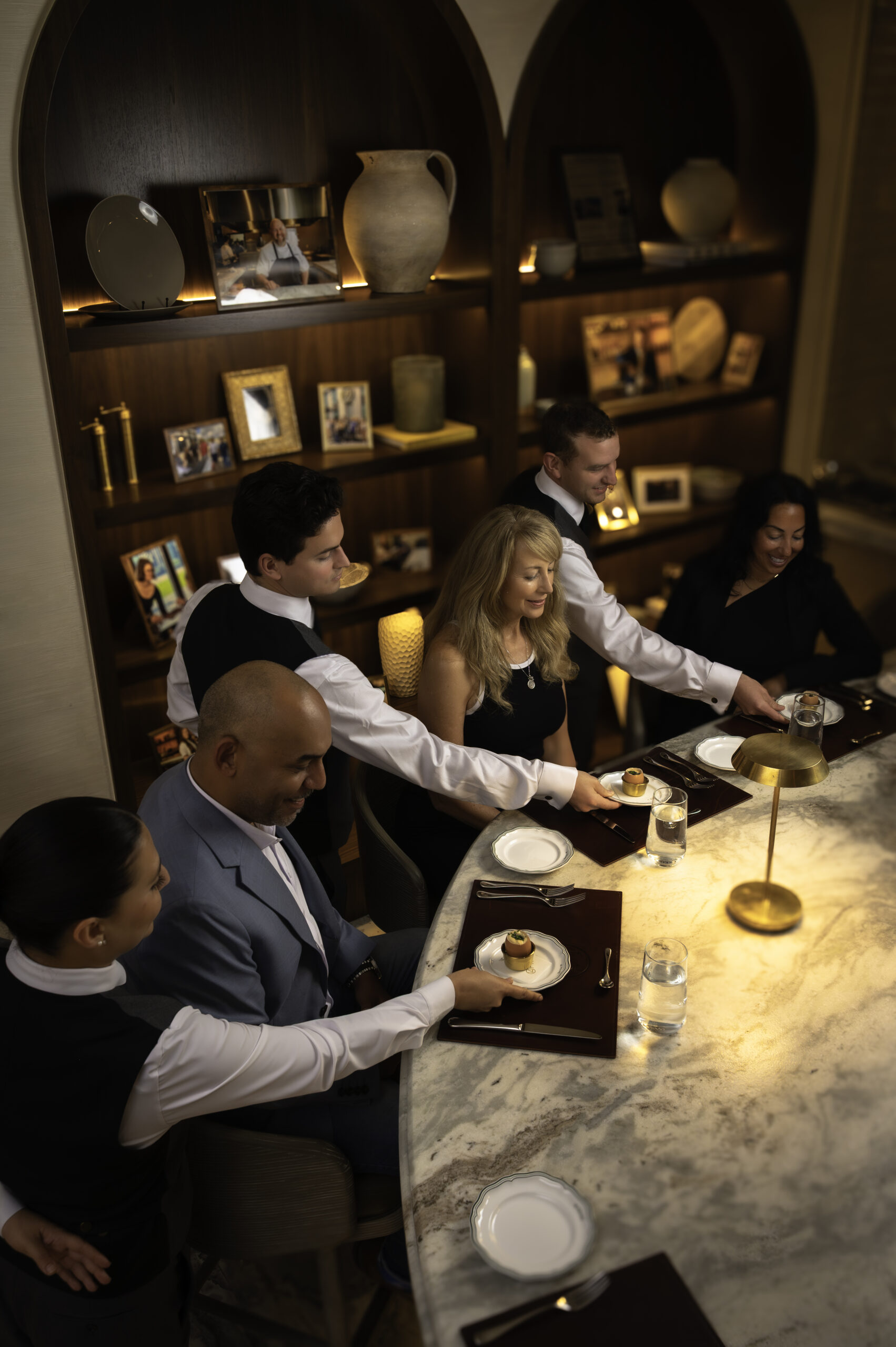 Severs dropping plates in sequence to guests at the Chef's Table